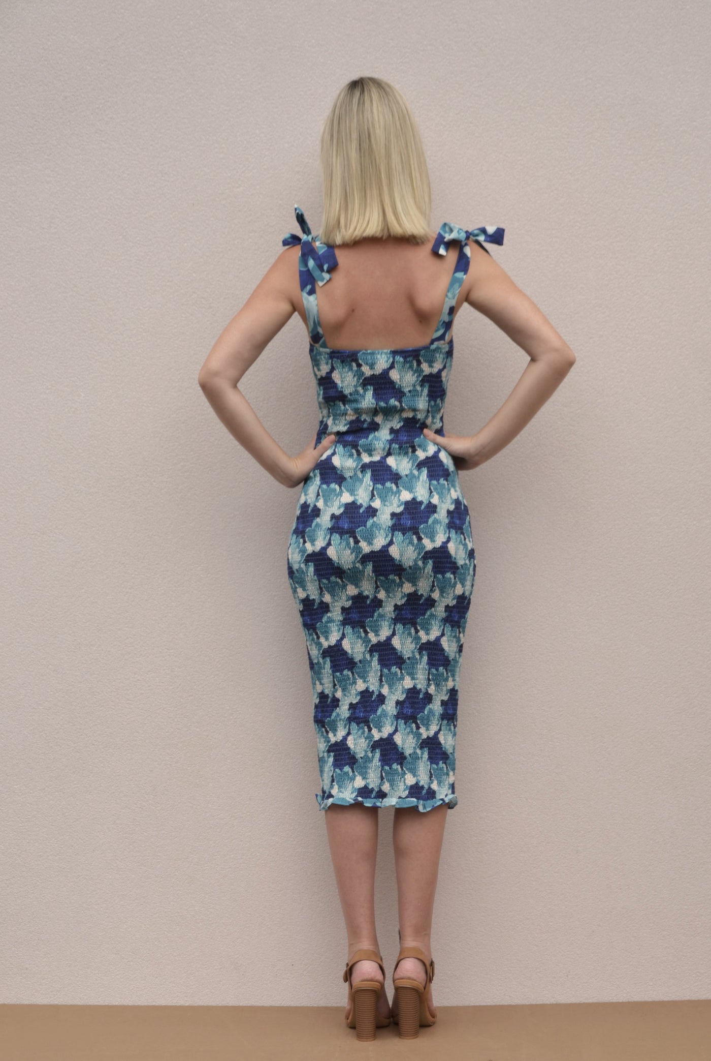 A shirred bodycon dress with tie up straps. A midi length dress with a blue floral pattern.