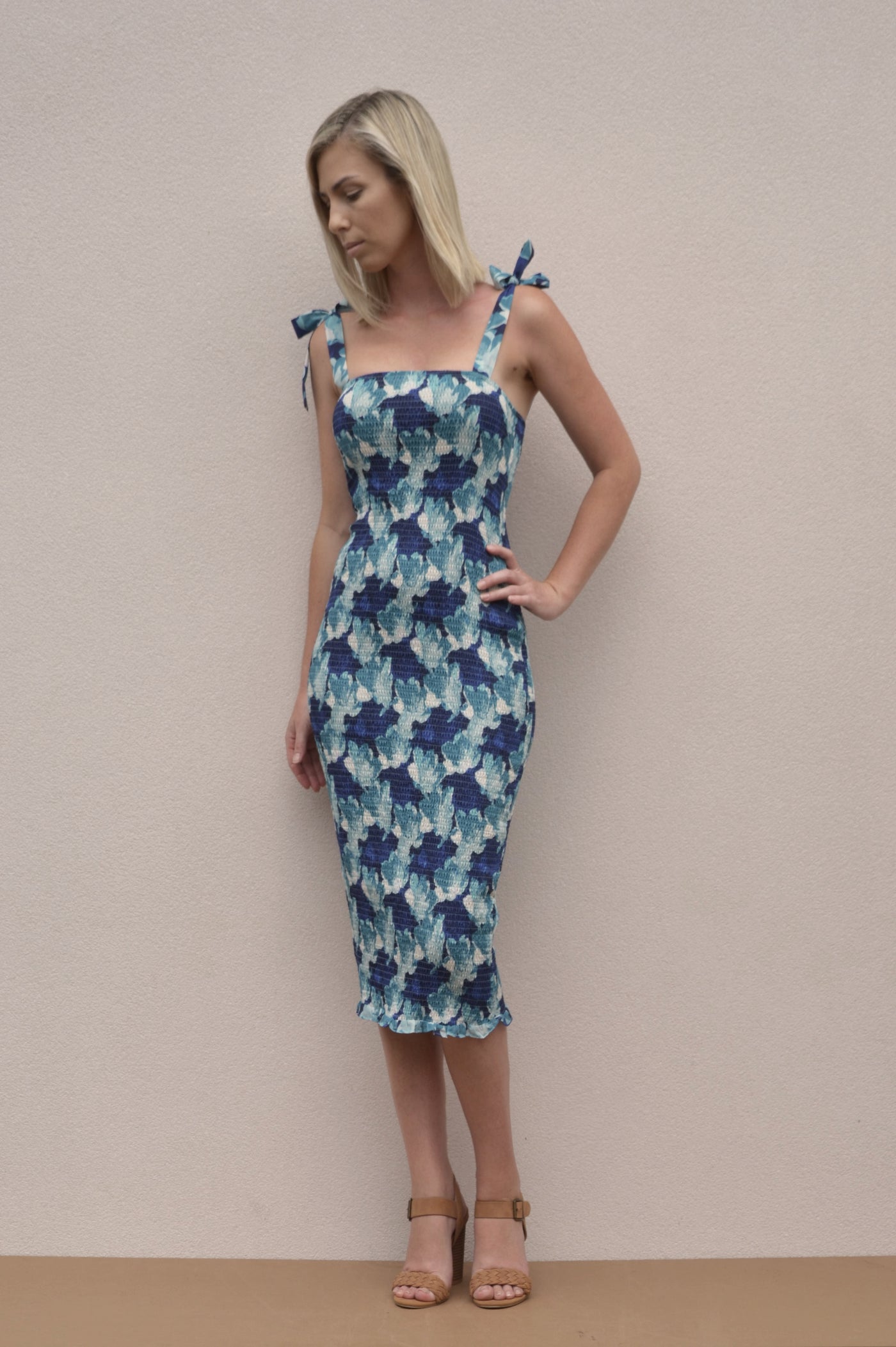 A shirred bodycon dress with tie up straps. A midi length dress with a blue floral pattern.