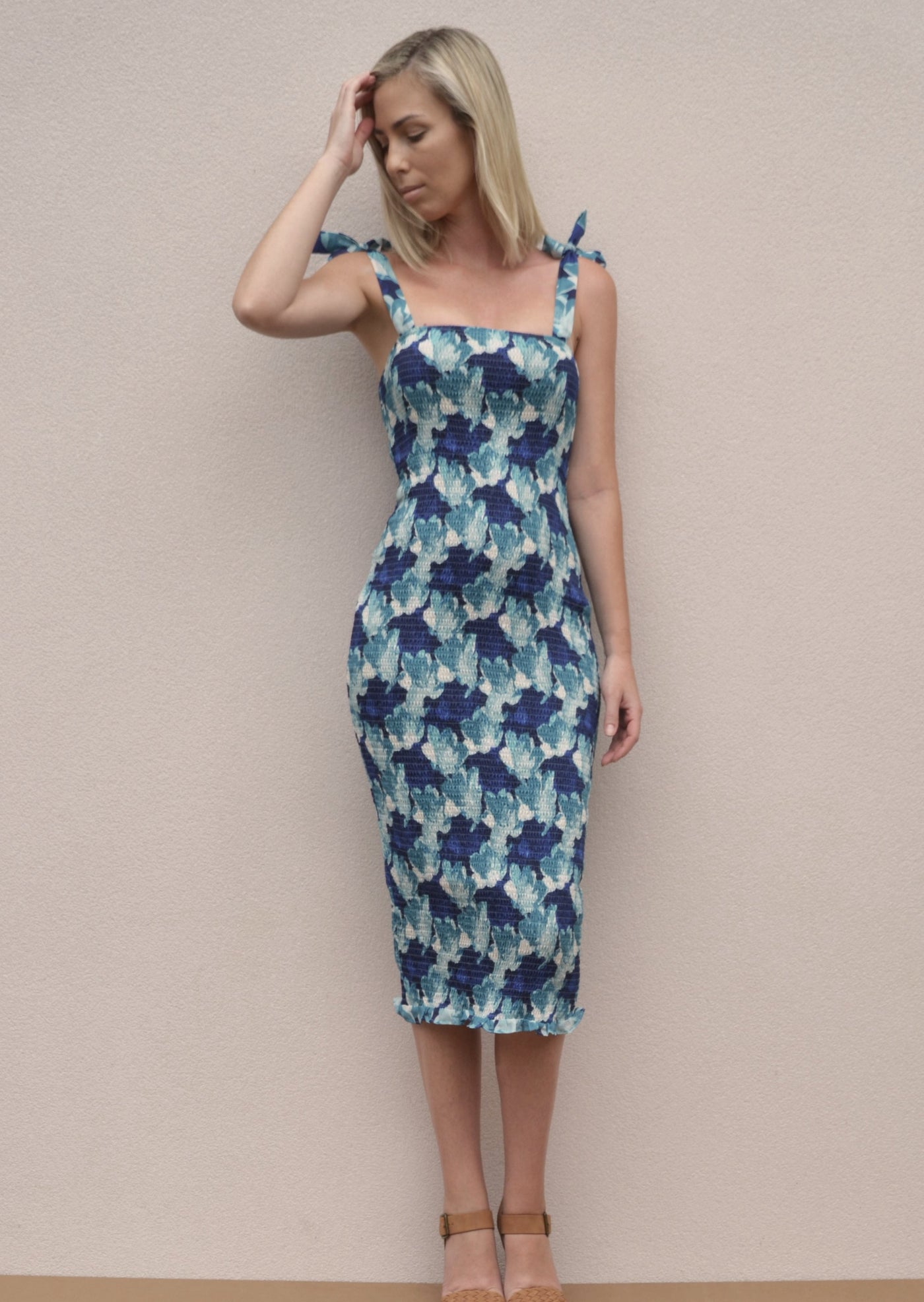 A shirred bodycon dress with tie up straps. A midi length dress with a blue floral pattern.