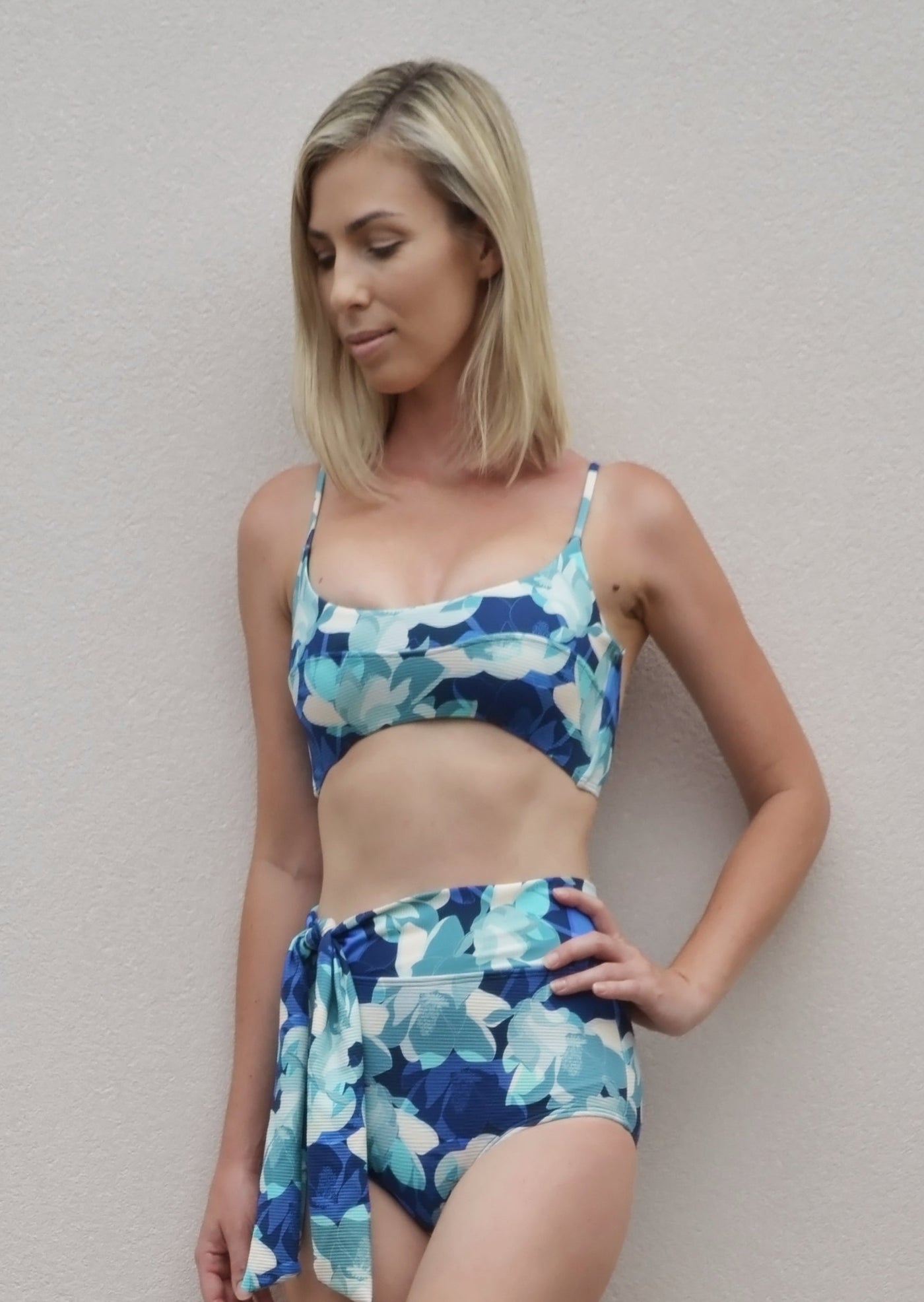 A  ribbed blue floral pattern bikini crop top with seam detail across the bust and thin straps. The bikini top is made from sustainable, recycled material