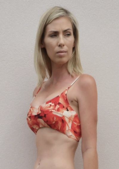 A  ribbed red floral pattern bikini crop top with seam detail across the bust and thin straps. The bikini top is made from sustainable, recycled material